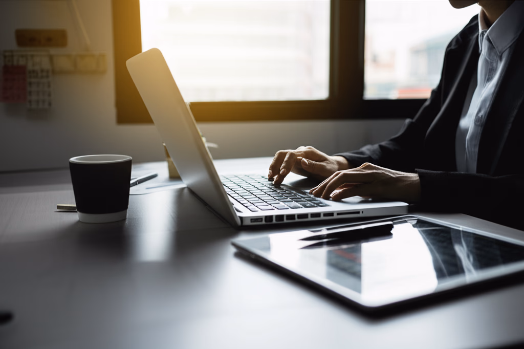 Professional reviewing notes and typing on laptop, symbolizing diligent meeting follow-up and post-meeting productivity in a modern office environment.