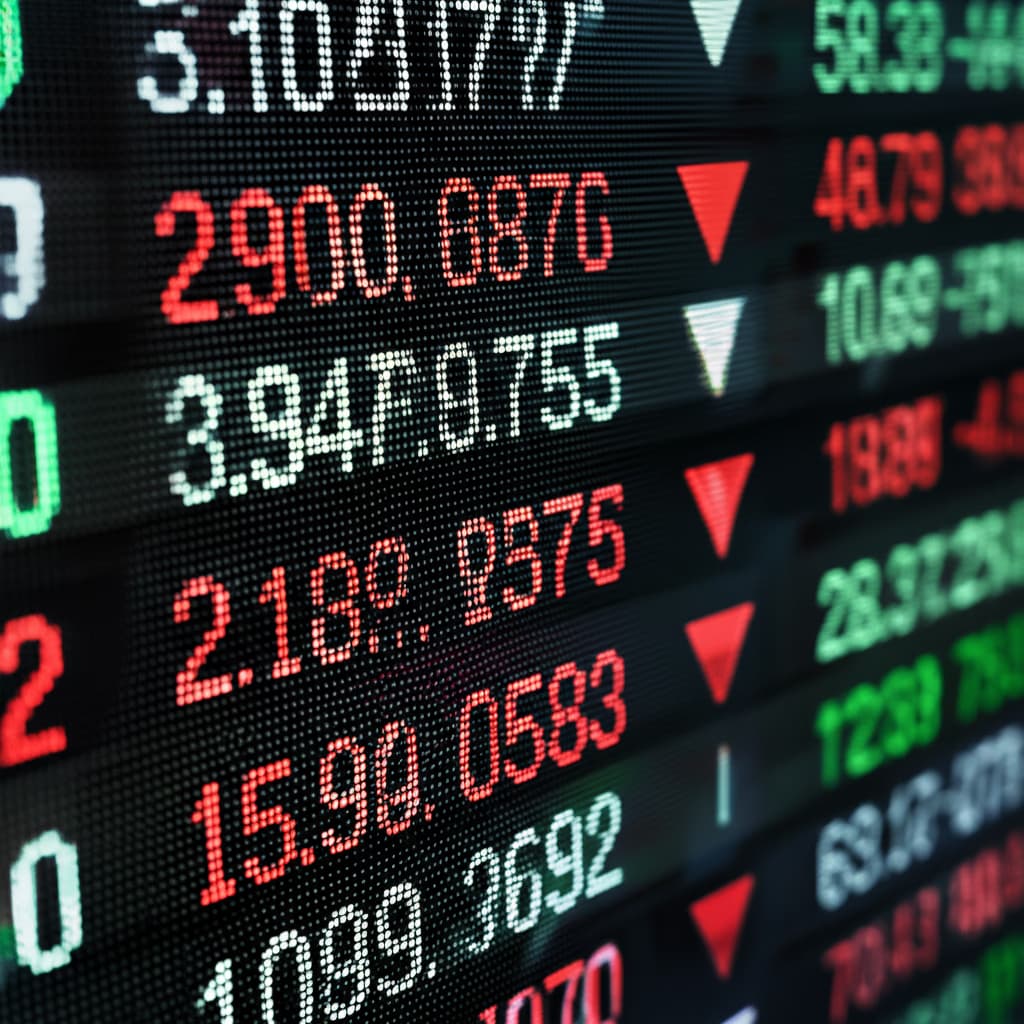 Close-up view of a vibrant digital stock ticker screen showing live financial market data, stock prices, and trading volume, with numbers scrolling and changing colors.